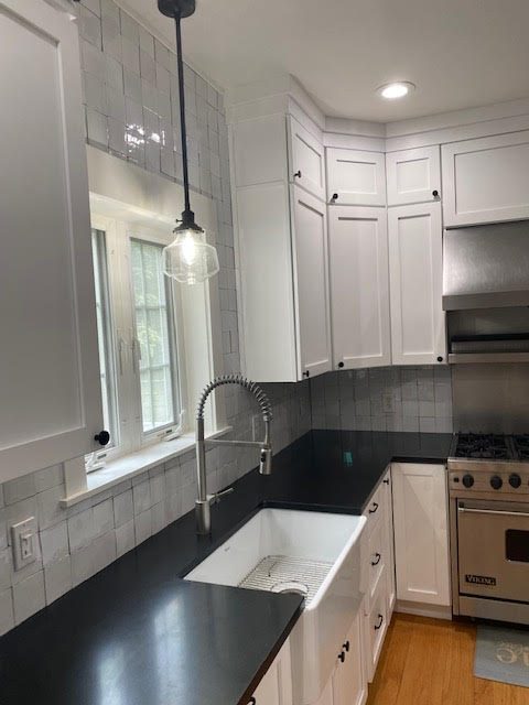 White kitchen with black countertops and farmhouse sink